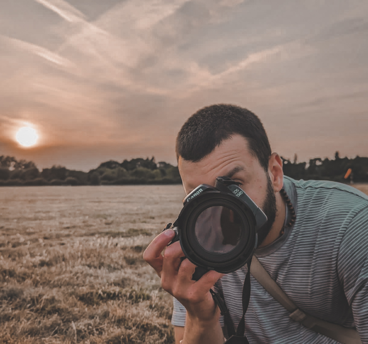 picture of luke rebeiro  holding a camera with a sunset in the background